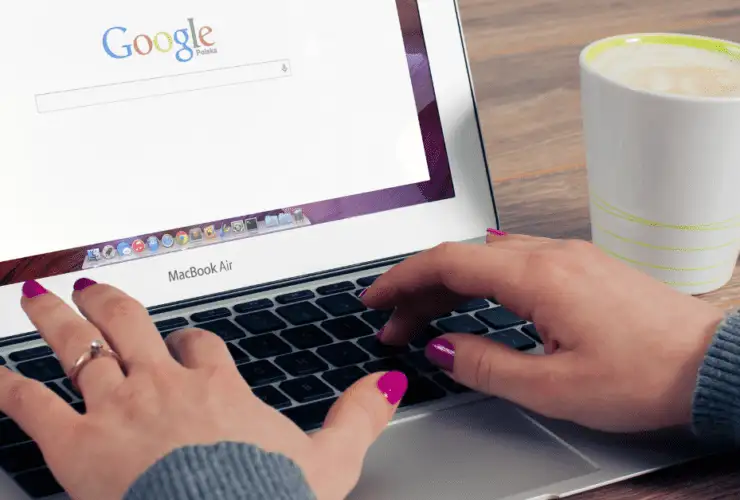 Laptop open on google with hands typing on the keyboard