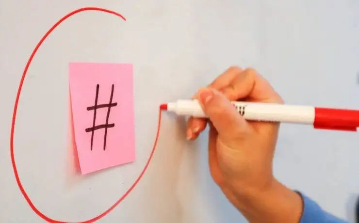 Person circling the hashtag symbol on a piece of paper with a marker - Illustration for understanding hashtags