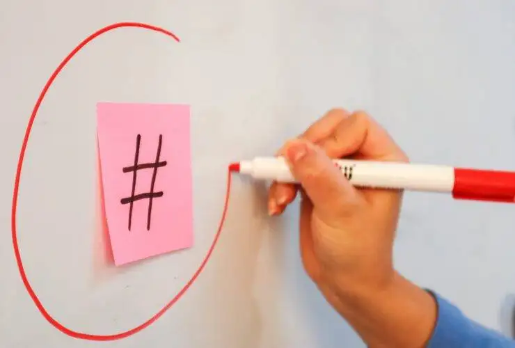 Person circling the hashtag symbol on a piece of paper with a marker - Illustration for understanding hashtags